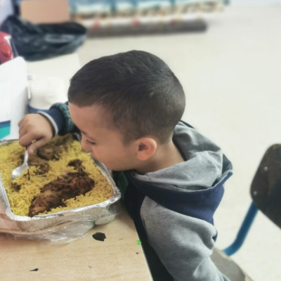 Displaced child in Lebanon eating a hot meal.